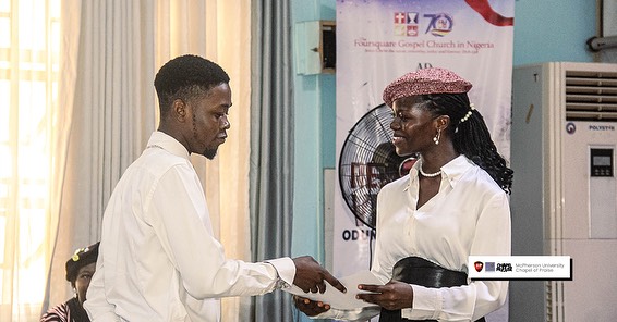 A lady handing a WIT certificate to a boy